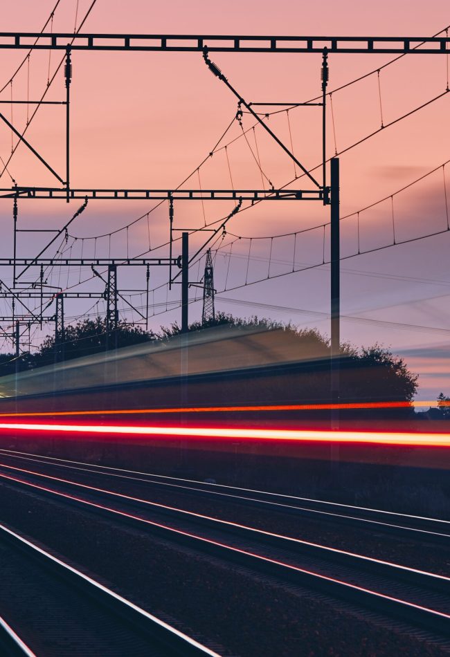 Railway at dawn. Light trails of passenger train on modern railroad track.